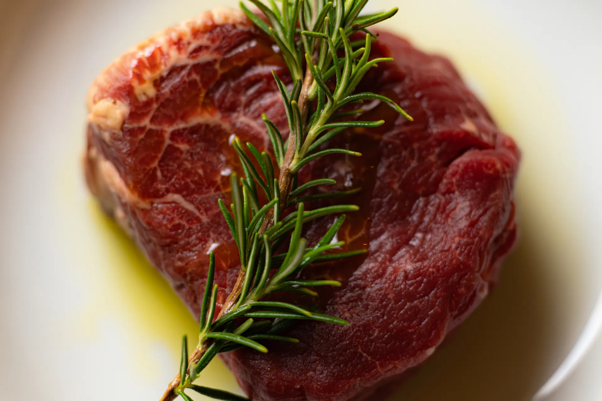 Rindsfilet mit Rosmarinzweig in Olivenöl, bereit für den Grill