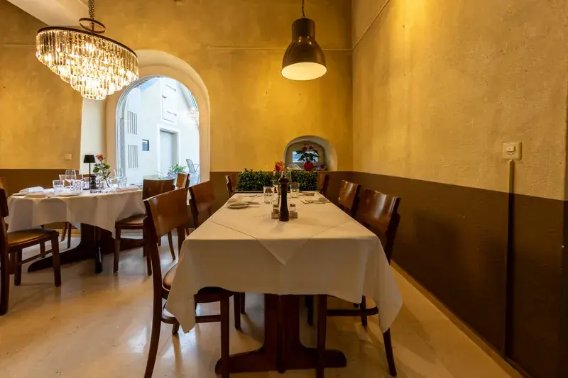 Dining room at LAGO Horgen with a crystal chandelier, an arched window and white-clothed tables