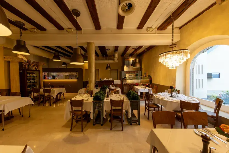 Dining room with a chandelier and arched window, tables set for dinner at LAGO Horgen